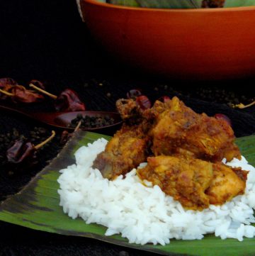 Indian chicken curry served over rice on banana leaf