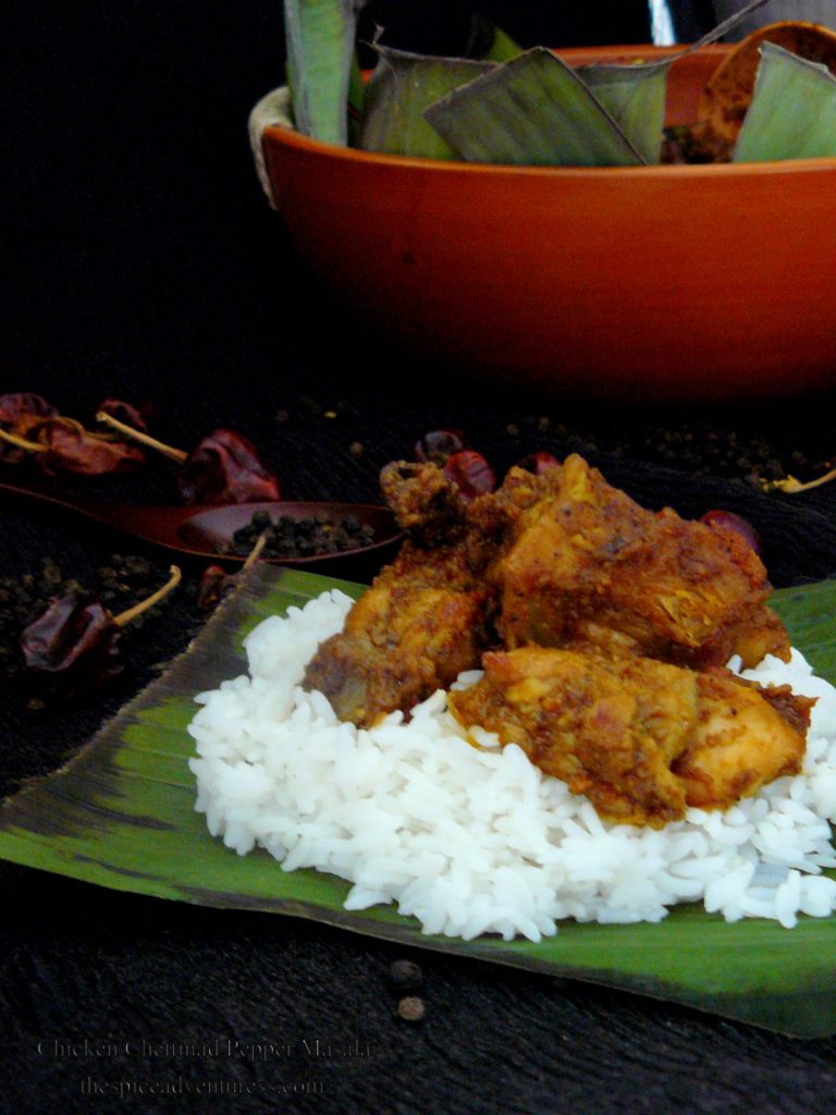 Indian chicken curry served over rice on banana leaf