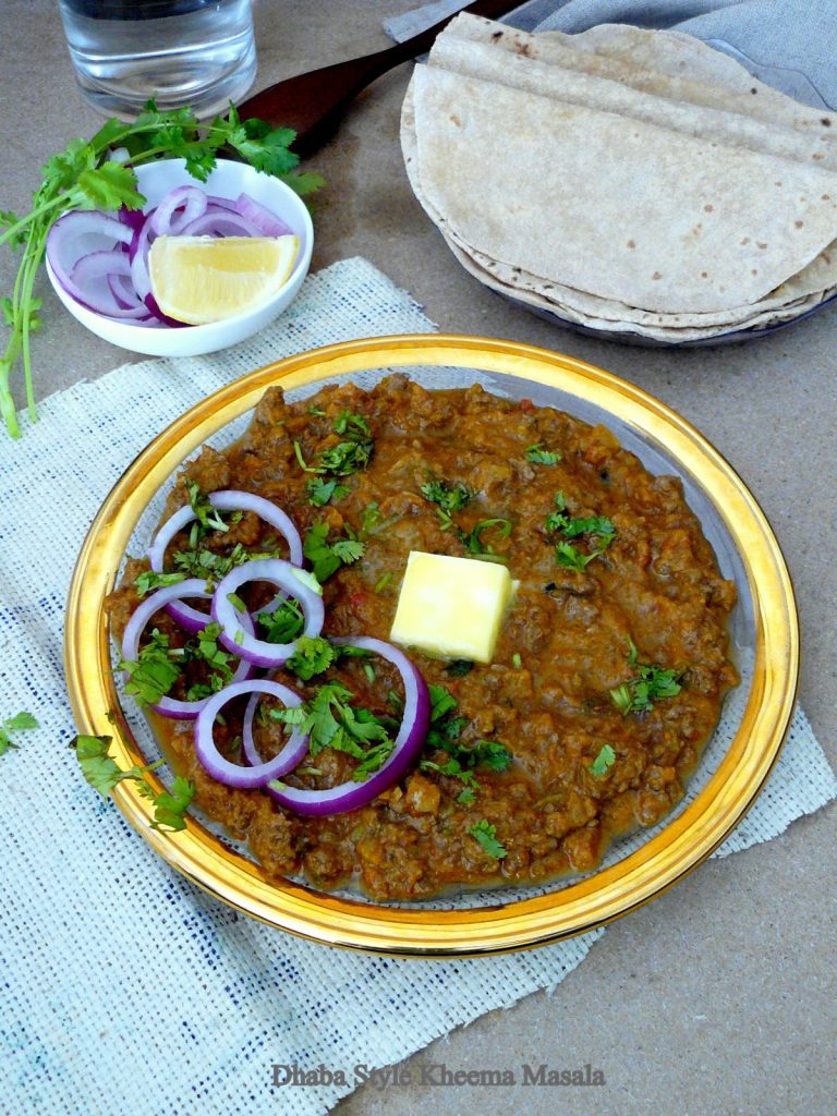 Lamb mince curry garnished with butter and onions and flatbreads on the side