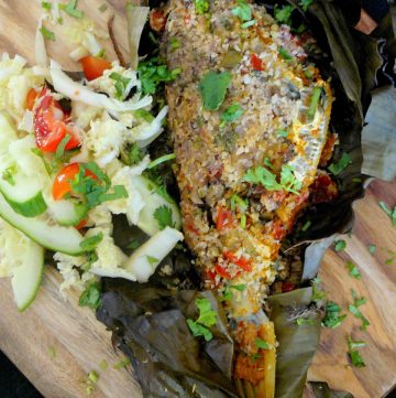 Grilled whole fish in banana leaf served with salad on the side