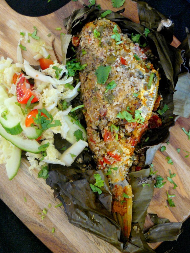 Grilled whole fish in banana leaf served with salad on the side