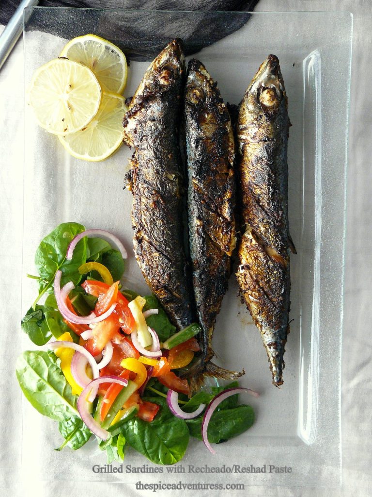 Three grilled sardines with salad and lemon slices