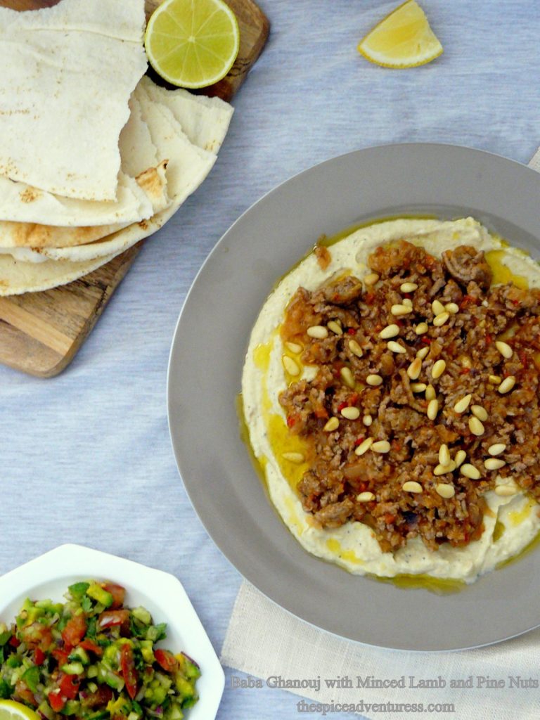 Hummus topped with minced lamb and pine nuts, pita bread and salad