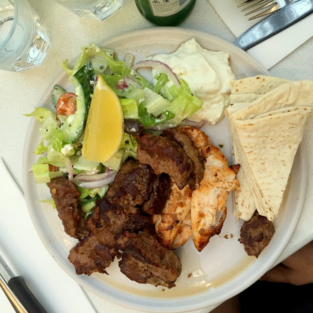Open style souvlaki with both grilled lamb and chicken served with a Greek salad, lemon, tzatziki and pita bread