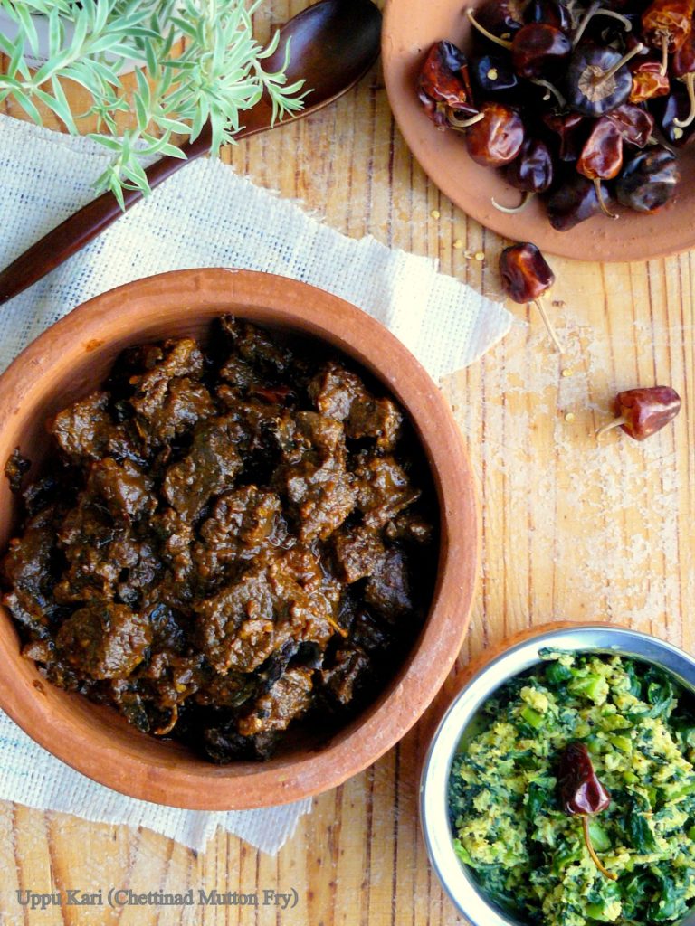 Indian style goat curry in terracotta bowl with dried red chillies in the background