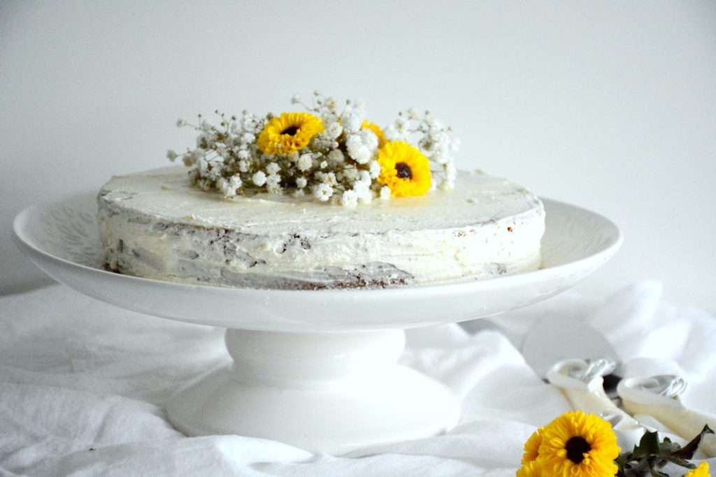 Lemon cake decorated with edible flowers on white stand