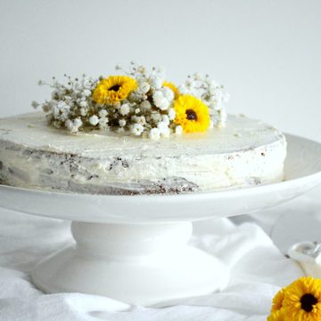 Lemon cake decorated with edible flowers on white stand