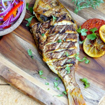 Indian style grilled whole snapper on wooden board