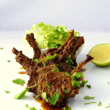Lamb chops with lettuce and lime slice on white plate