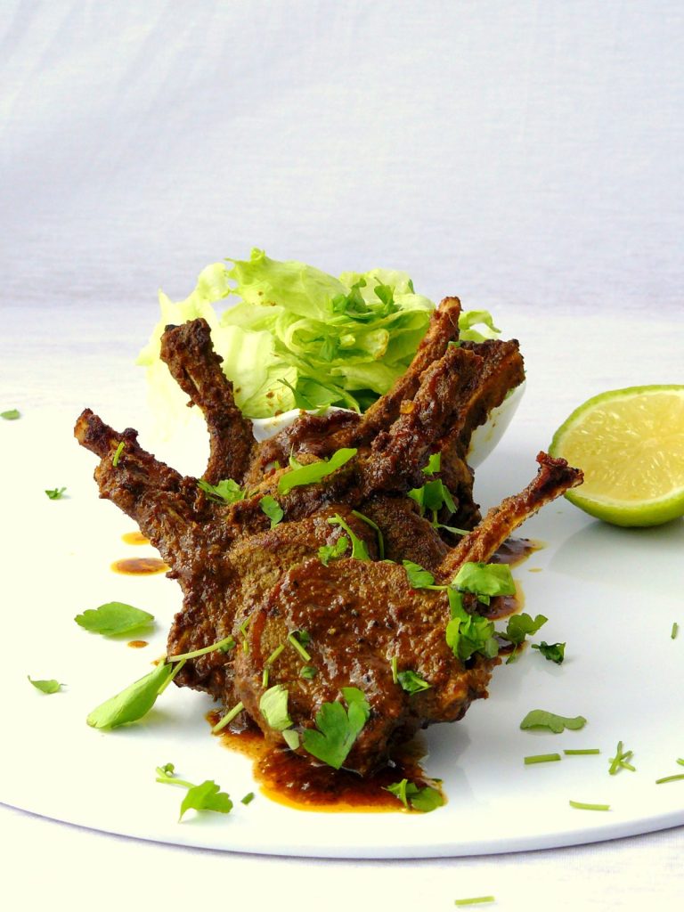 Lamb chops with lettuce and lime slice on white plate