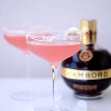 Two glasses of pink cocktail with a bottle of Chambord in the background