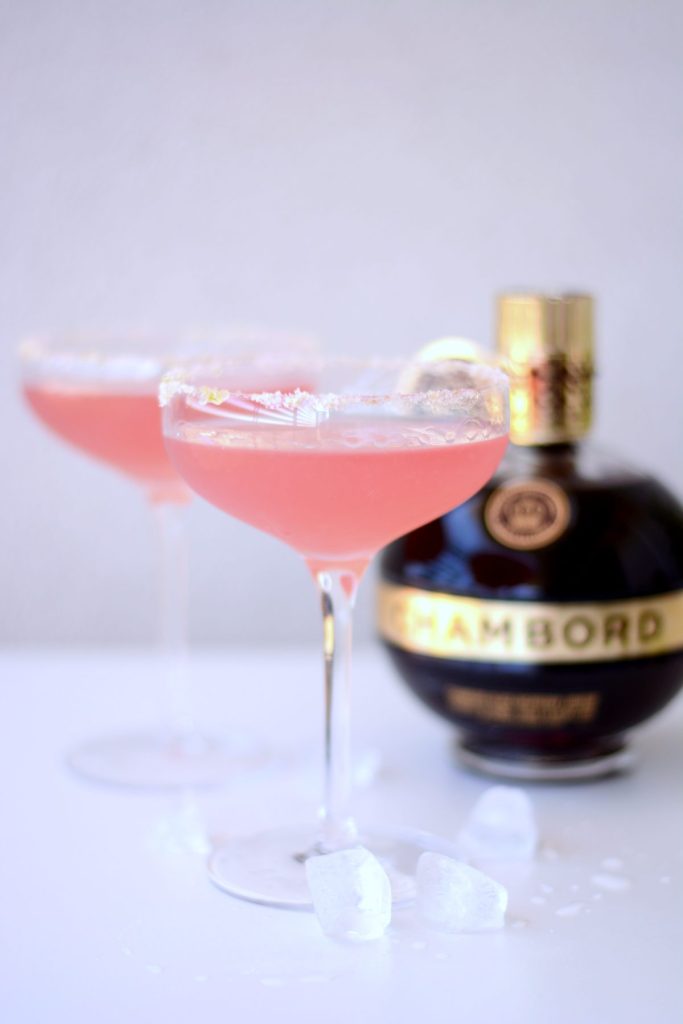 Two glasses of pink cocktail with a bottle of Chambord in the background