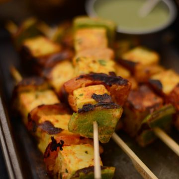 Grilled paneer skewers on black tray