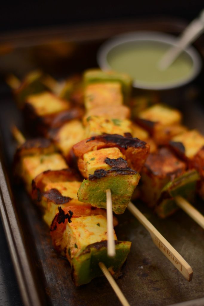 Grilled paneer skewers on black tray