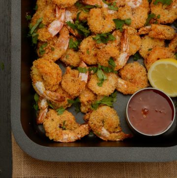 Crumbed prawns in black baking tray