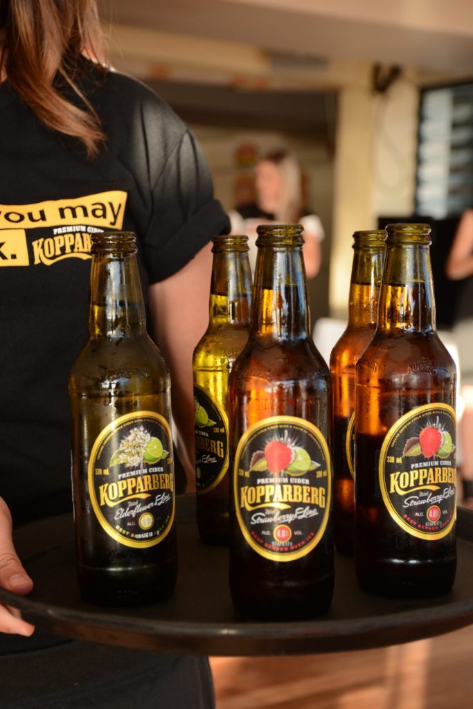 Lady carrying tray with bottles of Kopparberg cider