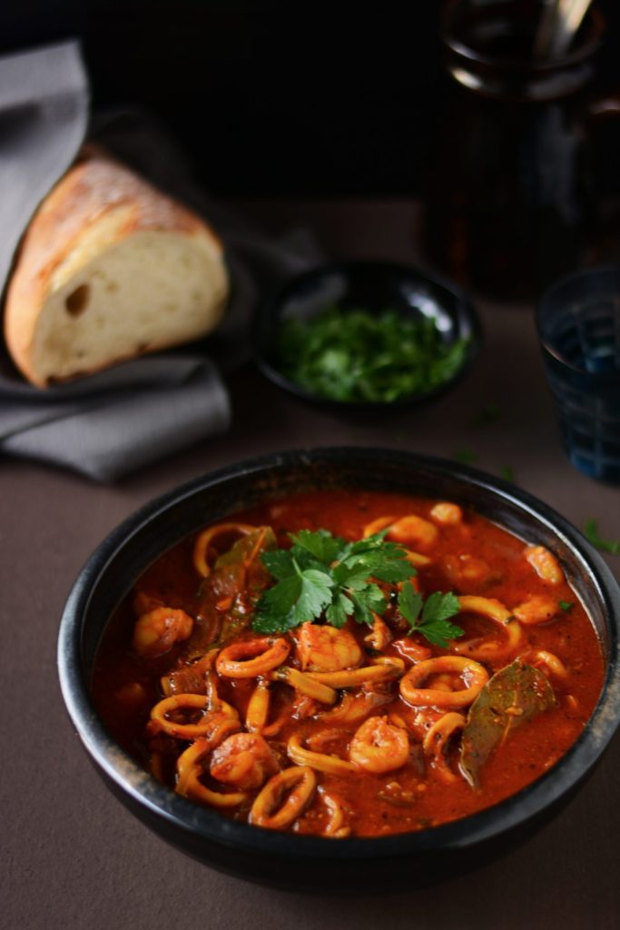 Squid, prawn and saffron stew in black bowl