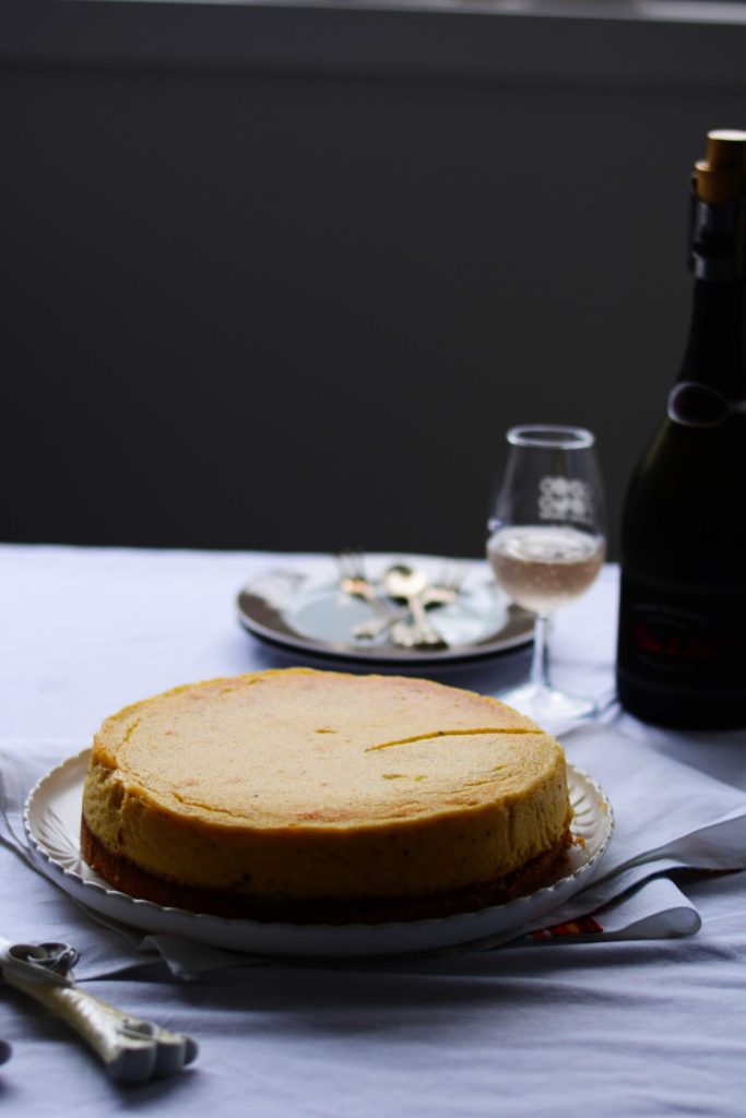 Vanilla cardamom cheesecake with a glass of wine on the side