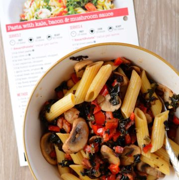 Pasta with kale, bacon and mushrooms served in cream coloured bowl