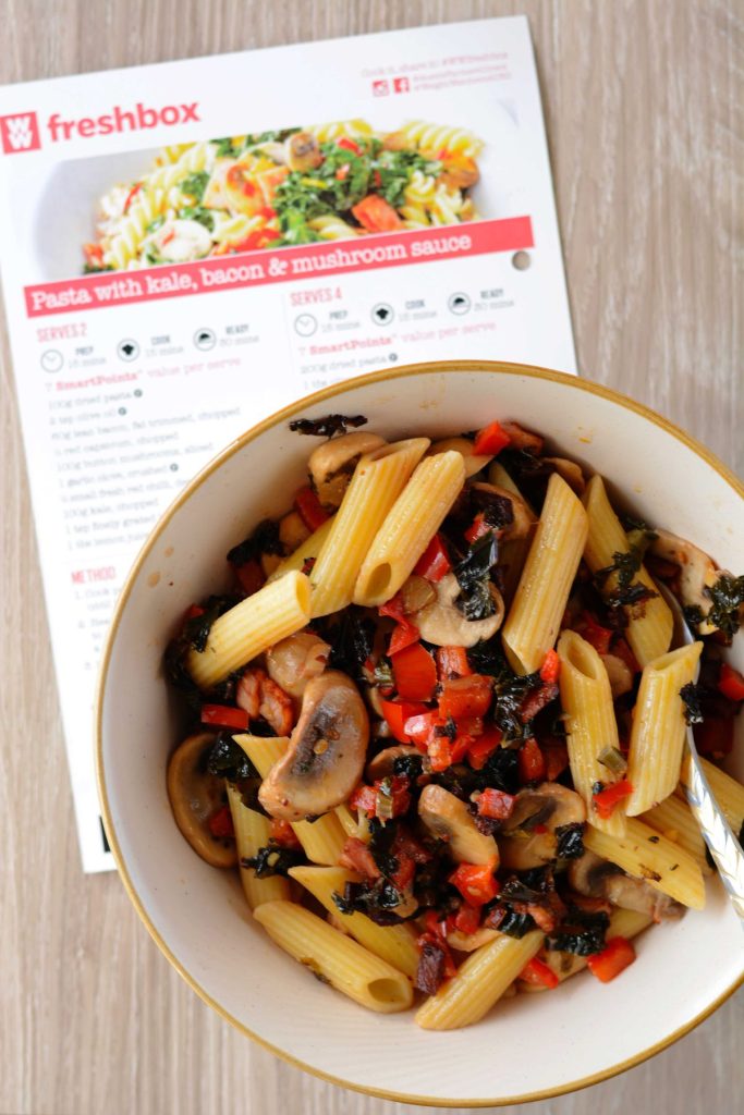 Pasta with kale, bacon and mushrooms served in cream coloured bowl