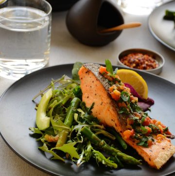 Pan fried salmon with green salad served on black plate