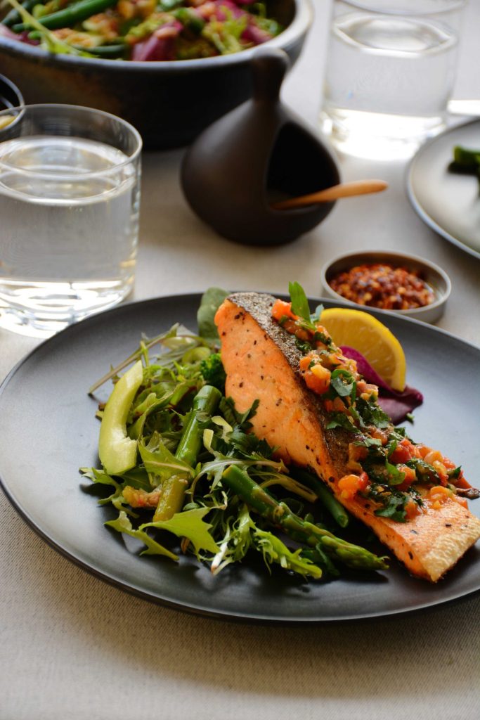 Pan fried salmon with green salad served on black plate