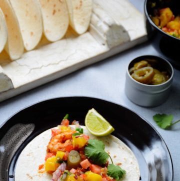 Prawn taco with mango salsa served on brown plate