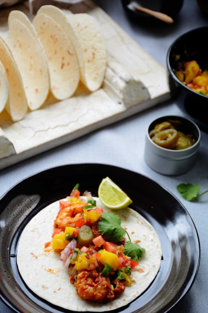 Prawn taco with mango salsa served on brown plate