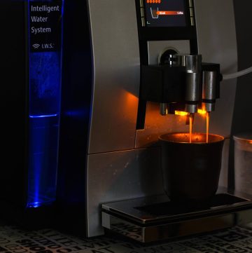 A black and silver automatic coffee machine dispensing coffee