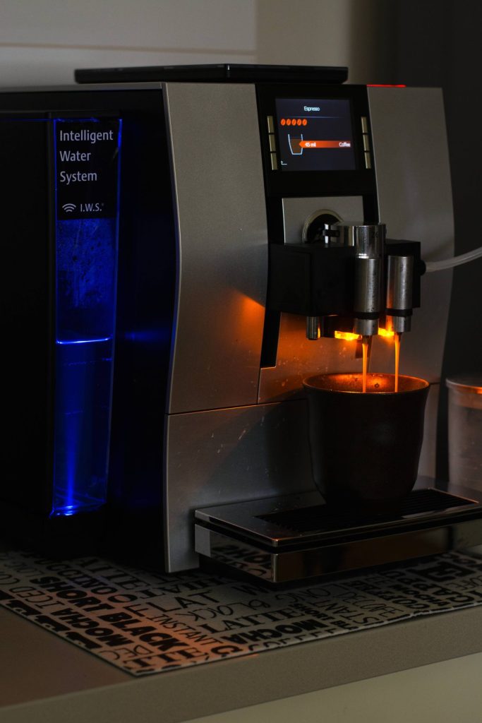 A black and silver automatic coffee machine dispensing coffee