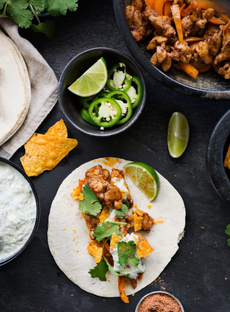 Chicken fajita taco with slices of lime, jalapeno on the side