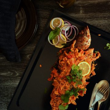 Whole grilled barramundi on a black tray