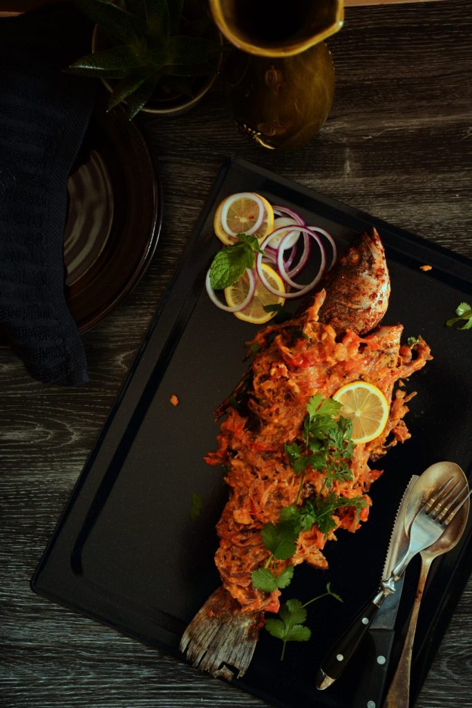 Whole grilled barramundi on a black tray