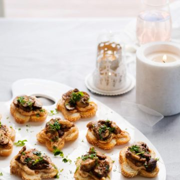 A white platter with lots of mini mushroom and hummus toasties