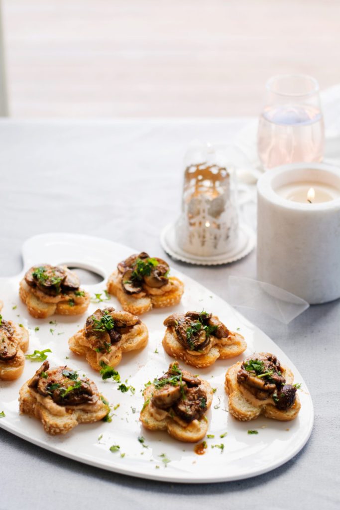 A white platter with lots of mini mushroom and hummus toasties