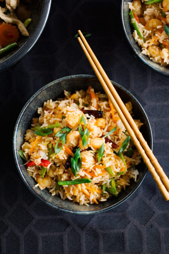 Prawn fried rice served in black bowl with a pair of chopsticks on top