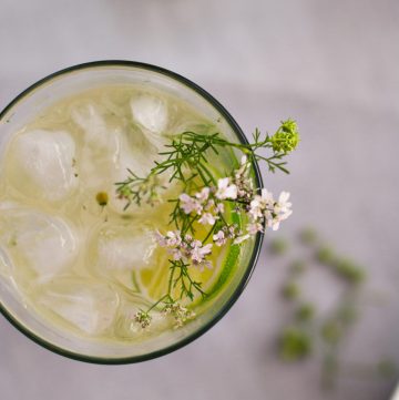 Top view of Mojito cocktail in a glass garnished with lime slices and edible flowers