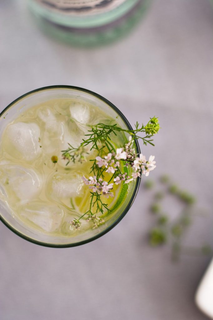 Top view of Mojito cocktail in a glass garnished with lime slices and edible flowers