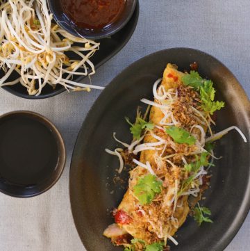 Stuffed prawn omelette served on oval shaped black plate with a side of bean sprouts