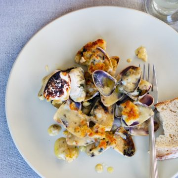 A grey plate with baked clams and a fork