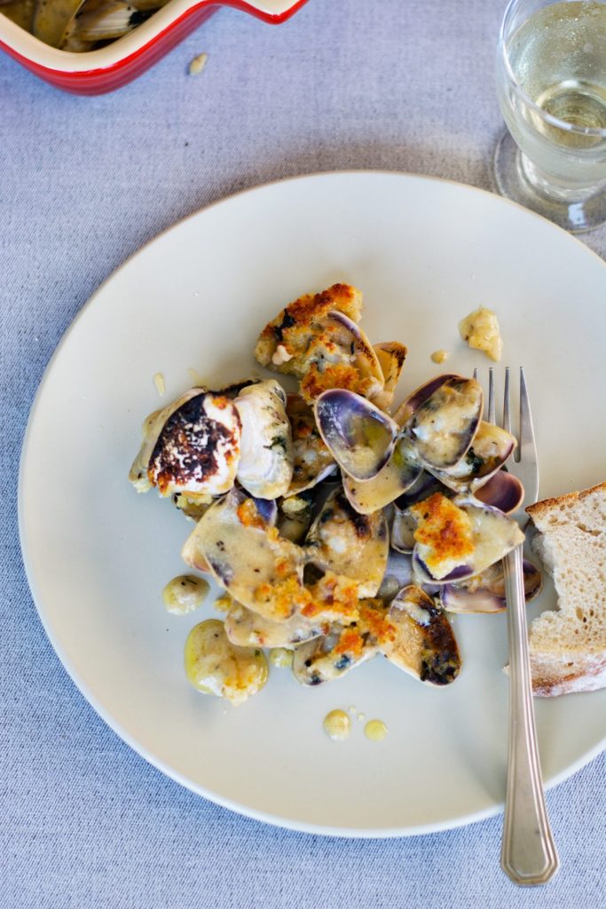 A grey plate with baked clams and a fork