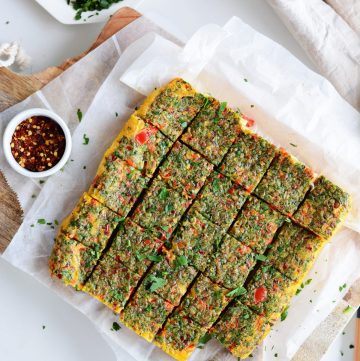 Cubes of baked eggs with herbs on white baking paper