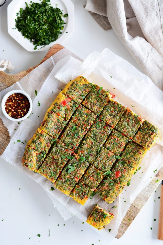 Cubes of baked eggs with herbs on white baking paper