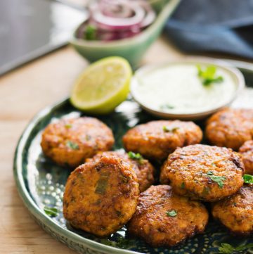 salmon kebabs served in green plate with lime slice on the side