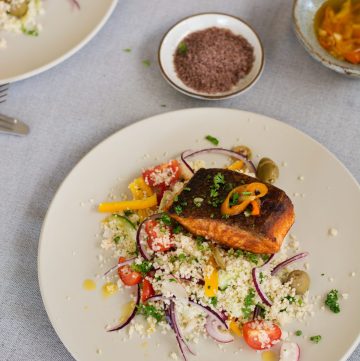 Fried salmon on top of couscous salad served on cream coloured plate