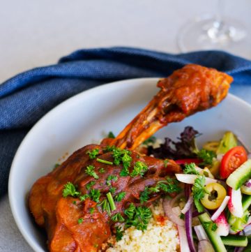 slow cooked lamb shank served with couscous and salad in blue bowl
