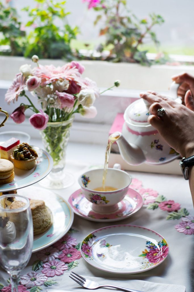 Hand pouring tea from pot into cup