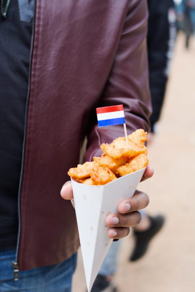Hand holding fried nuggets in paper cone