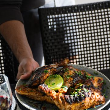 Man placing a plate of tandoori chicken thighs on the table