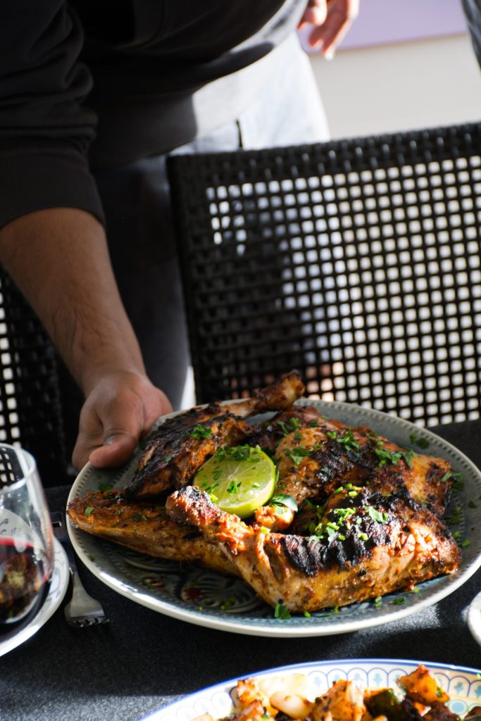 Man placing a plate of tandoori chicken thighs on the table